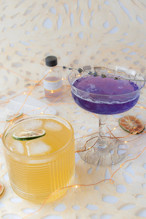 Two cocktails on a decorative table with string lights